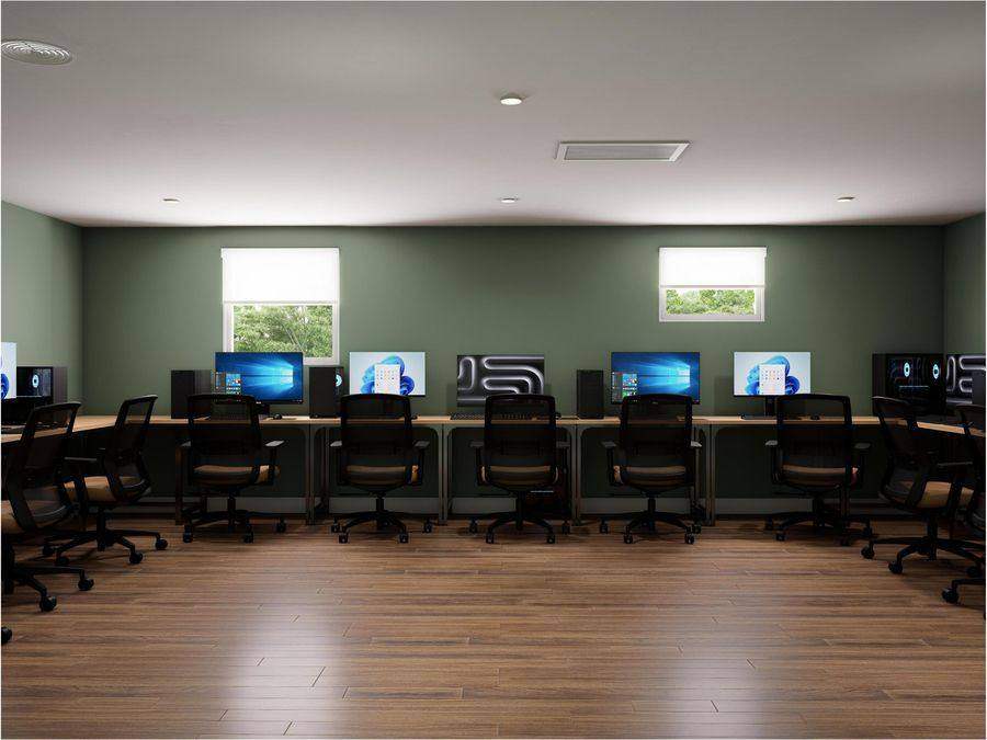 A computer room with a row of desks and monitors